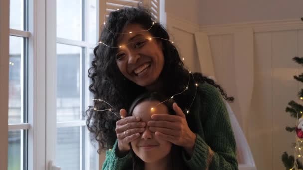 Brunette girl and black mother hug wrapped with garland — Vídeo de Stock