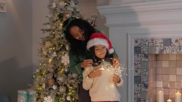 African American mother and daughter jump against Christmas tree — Vídeos de Stock