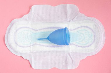 Menstrual cup lies on a pad on a pink background