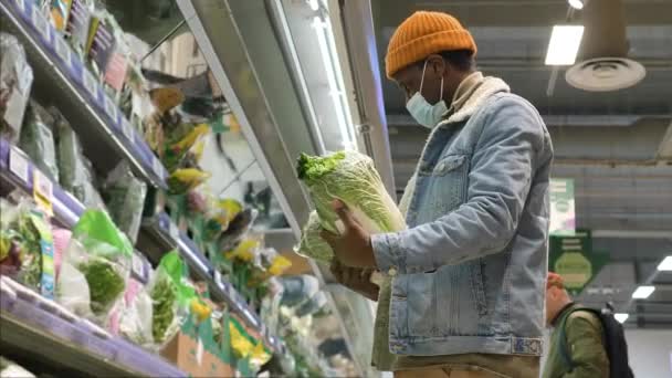 Black guy shopper chooses fresh lettuce in grocery fridge — Stok video