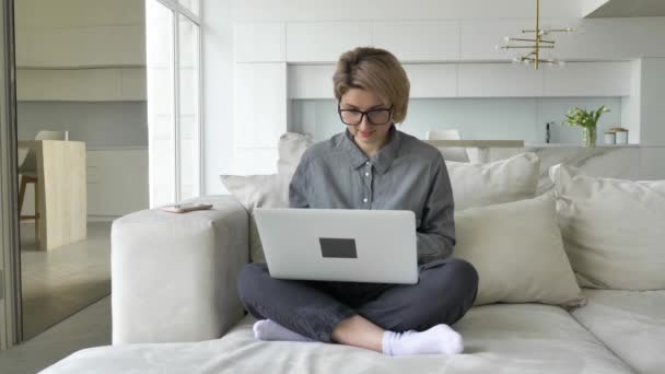 Young woman freelancer with short fair hair types on laptop — Vídeo de Stock