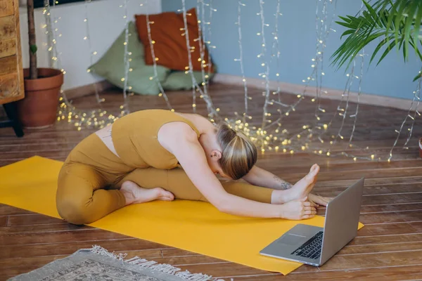 Молодая женщина делает упражнения йоги на мат с онлайн Lasson — стоковое фото