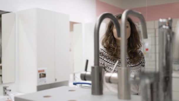 Młoda kobieta wybiera kran łazienkowy w sklepie z narzędziami — Wideo stockowe