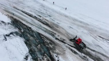 Buldozer yolda gider ve dağlık alanda kar temizler.