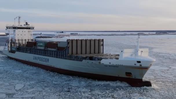 Un gran buque de carga con contenedores flota en el mar en medio del hielo en invierno — Vídeo de stock