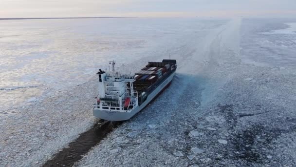 Большое судно с грузовыми контейнерами идет вдоль морского фарватера посреди льда — стоковое видео