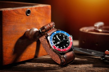 closeup luxury wristwatch for men with black dial blue-red bezel and leather strap. clipart