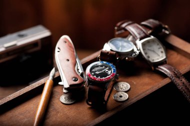 closeup luxury wristwatch for men with black dial blue-red bezel and leather strap. wristwatch with vintage men's objects.