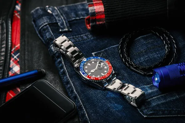男性用アクセサリー ブラックダイヤルブルーレッドベゼルとステンレススチールブレスレットと腕時計でクローズ ストック写真