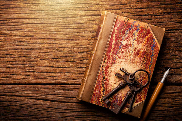 antique leather bound book with marbling paper cover on wooden table.