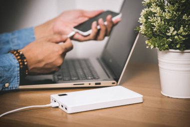 Boş akü akıllı telefonunu beyaz enerji bankasıyla şarj ediyor. Sığ alan derinliği.