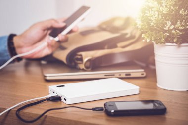 Boş akü akıllı telefonunu beyaz enerji bankasıyla şarj ediyor. Sığ alan derinliği.