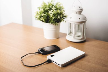 Boş akü akıllı telefonunu beyaz enerji bankasıyla şarj ediyor. Sığ alan derinliği ve filtrelenmiş.