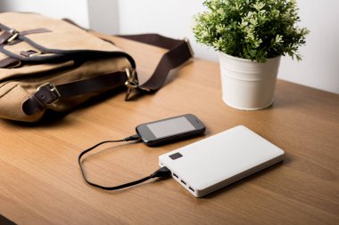 Boş akü akıllı telefonunu beyaz enerji bankasıyla şarj ediyor. Sığ alan derinliği.