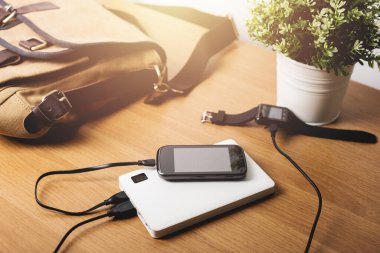 Boş akü akıllı telefonunu beyaz enerji bankasıyla şarj ediyor. Sığ alan derinliği.