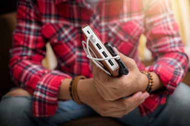 Kırmızı gömlekli adam akıllı telefonu beyaz güç bankasıyla şarj ediyor.. 