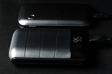 Akıllı telefonun bataryasını siyah güç bankasıyla şarj etmek. 