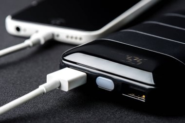 Akıllı telefonun bataryasını siyah güç bankasıyla şarj etmek. 