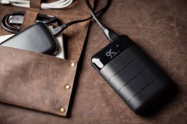 Siyah güç bankası USB kablosuna bağlı. Elektrik bankasıyla elektronik cihazı şarj ediyorum. Güç bankası görüntüsüne odaklanmış sığ alan derinliği.
