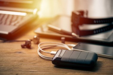 Siyah güç bankası USB kablosuna bağlı. Akıllı telefonu güç bankasıyla şarj ediyor. Güç bankası görüntüsüne odaklanmış sığ alan derinliği.