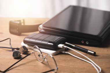 Siyah güç bankası USB kablosuna bağlı. Akıllı telefonu güç bankasıyla şarj ediyor. Güç bankası görüntüsüne odaklanmış sığ alan derinliği.