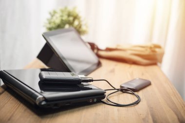 Siyah güç bankası USB kablosuna bağlı. Akıllı telefonu güç bankasıyla şarj ediyor. Güç bankası görüntüsüne odaklanmış sığ alan derinliği.