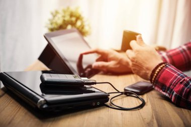 Siyah güç bankası USB kablosuna bağlı. Akıllı telefonu güç bankasıyla şarj ediyor. Güç bankası görüntüsüne odaklanmış sığ alan derinliği.