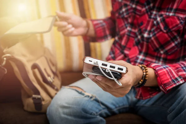 Kırmızı gömlekli adam akıllı telefonu beyaz güç bankasıyla şarj ediyor.. 