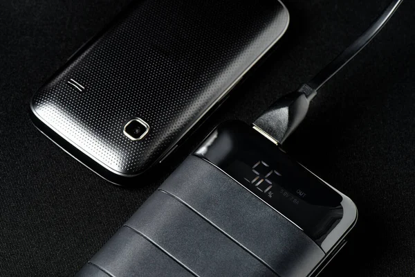 Akıllı telefonun bataryasını siyah güç bankasıyla şarj etmek. 