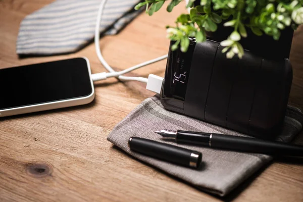 Siyah güç bankası USB kablosuna bağlı. Akıllı telefonu güç bankasıyla şarj ediyor. Güç bankası görüntüsüne odaklanmış sığ alan derinliği.