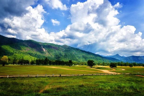 Bulutlu bir günde arka planda dağ sırasıyla güzel bir kır manzarası..