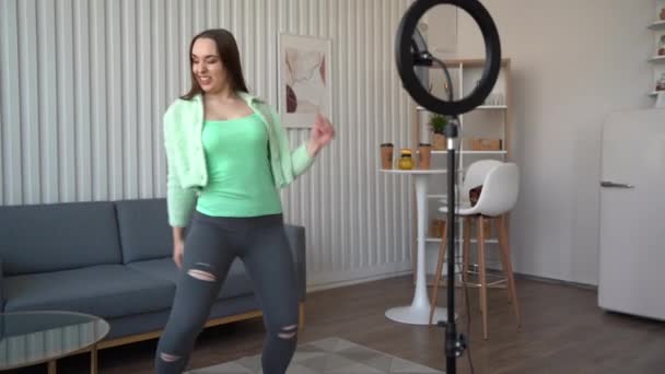 年轻女孩在相机前跳舞 用三脚架上的电话和家里的戒指灯 在移动应用上做出流行的内容 在社交媒体上分享 — 图库视频影像