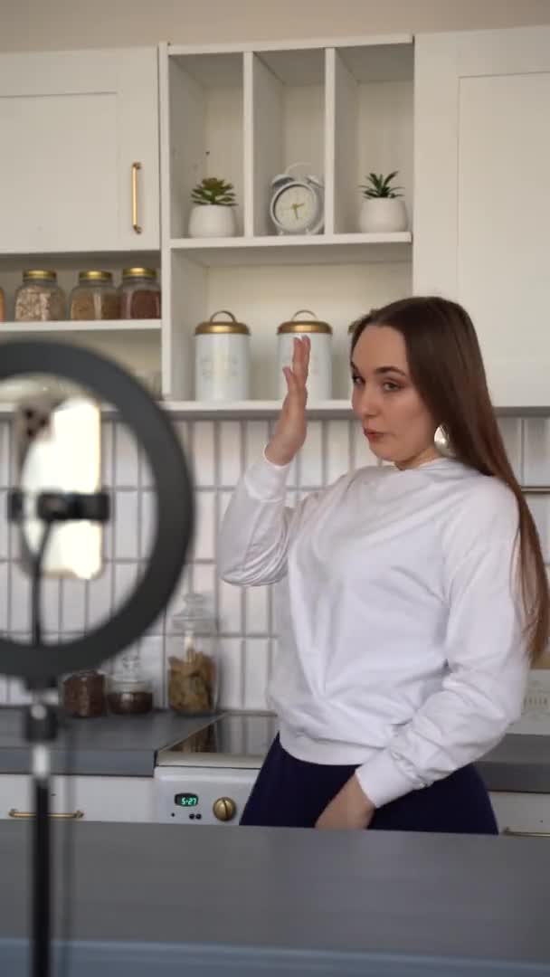 年轻的女博客记录了有趣的社交媒体视频 独自在家里跳舞 看手机摄像头 Vlogger正在为她的Vlog制作内容 — 图库视频影像