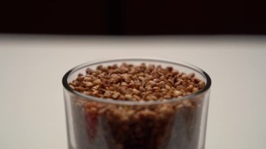 Cam bir şişede karabuğday yakın plan. Cam bir pikapta döner. Karabuğday lapasının kullanışlı özellikleri.