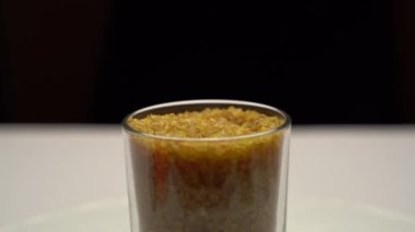 Cam bir şişede bulgur ezmesi yakın plan çekimi. Bir adamın eli bir çay kaşığı düşürür, bulgur toplar ve geri döker. Vücut için faydalı tahıllar.