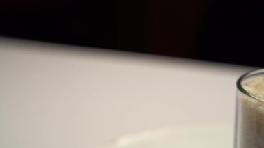 Yan çekim. Şeffaf bir kap beyaz pirinç masanın üzerinde duruyor. Yakın plan. Pirinç, Afrika, Doğu Asya, Avustralya ve Amerika 'da yetişen sağlıklı bir besindir..