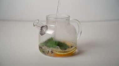 Çaydanlığa limon, portakal, nane yaprağı ve siyah çay ile kaynar su dök. Çay demleme süreci.