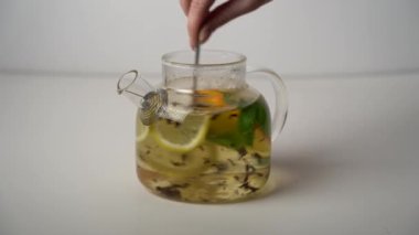 Çaydanlıktaki çayı kaşıkla karıştır. Citrus çayı bağışıklık sistemini güçlendirmek için. Detoksifikasyon için sağlıklı narenciye. Çay demleme süreci..