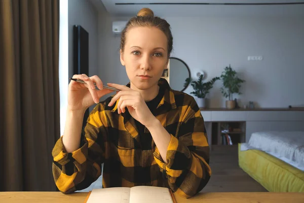 Girl at the desk, writing in the notebook 스톡 이미지