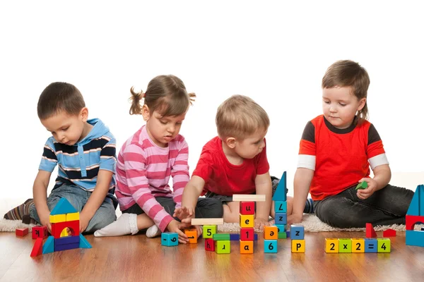 Vier Kinder spielen auf dem Fußboden — Stockfoto