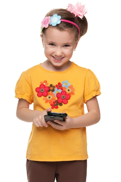 Little girl in a yellow shirt with smartphone — Stock Photo, Image