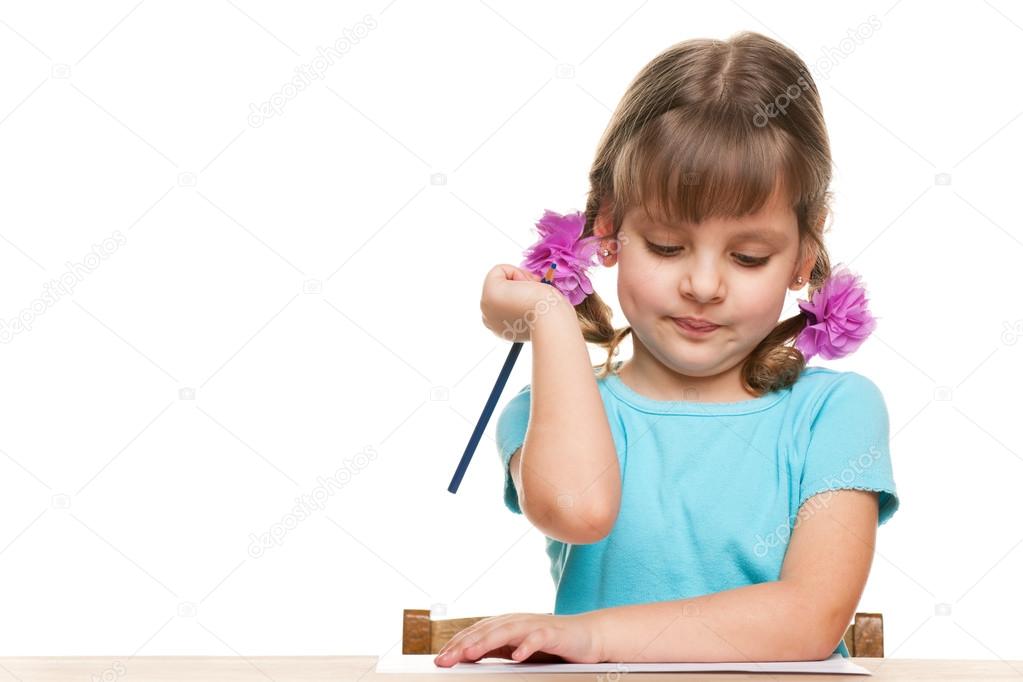 Little girl writes at the desk