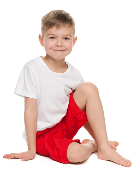 Улыбающийся мальчик сидит на полу — стоковое фото