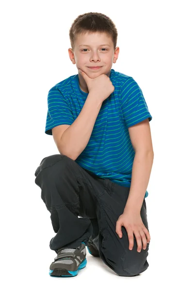 Fundersam pojke i blå tröja sitter på golvet — Stockfoto