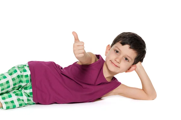 Lying boy holds his thumb up — Stock Photo, Image