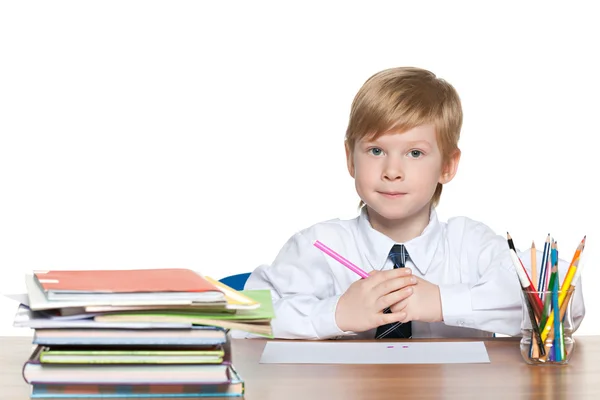 Rödhårig ung pojke sitter vid skrivbordet — Stockfoto