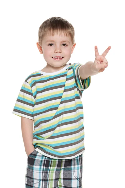 Jovem sorrindo menino mostra sinal de vitória — Fotografia de Stock