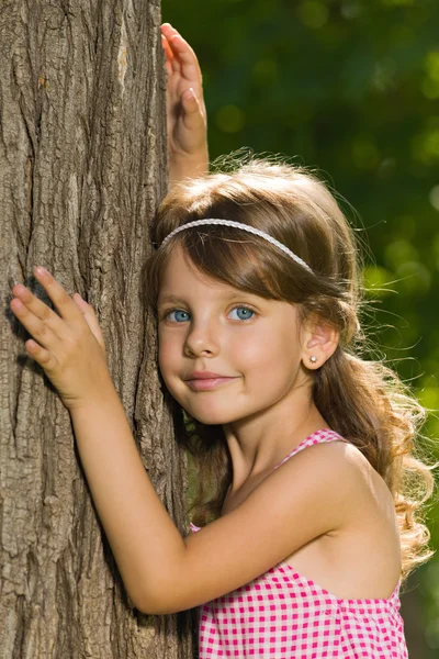 Pensive little girl near a tree — Stock Photo, Image