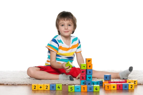 Petit garçon intelligent avec des blocs sur le sol — Photo