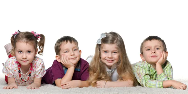 Four children lying on the carpet — Stock Photo, Image